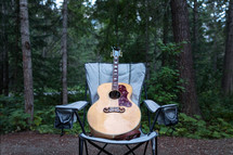 A guitar in a camping chair in the woods