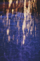 a blurred motion photo of a water fountain at night with lights