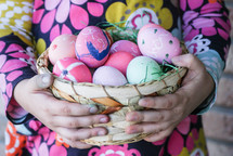 a child holding a basket of Easter eggs 