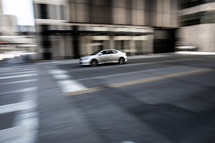 Panning shot of car on a city street which can give a sense of speed, urgency or even turmoil.