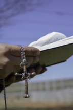 hands holding a cross and a Bible 