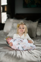 big sister holding a newborn baby 