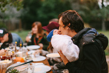 father kissing a baby at a fall dinner party outdoors 