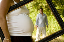 pregnant belly and father behind a frame carried by mother