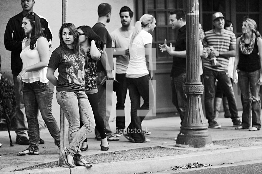 A group of young people socializing on the sidewalk girl alone on street outreach ministry young adults 