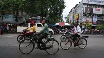 motorcycles, bicycles, pedestrians, and vehicles on a busy street 