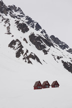 red lodges at the bottom of snow covered mountain peaks 