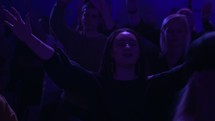 raised hands in an audience and purple stage lights 