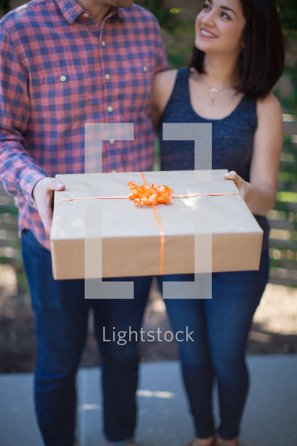 a couple holding a wrapped gift 