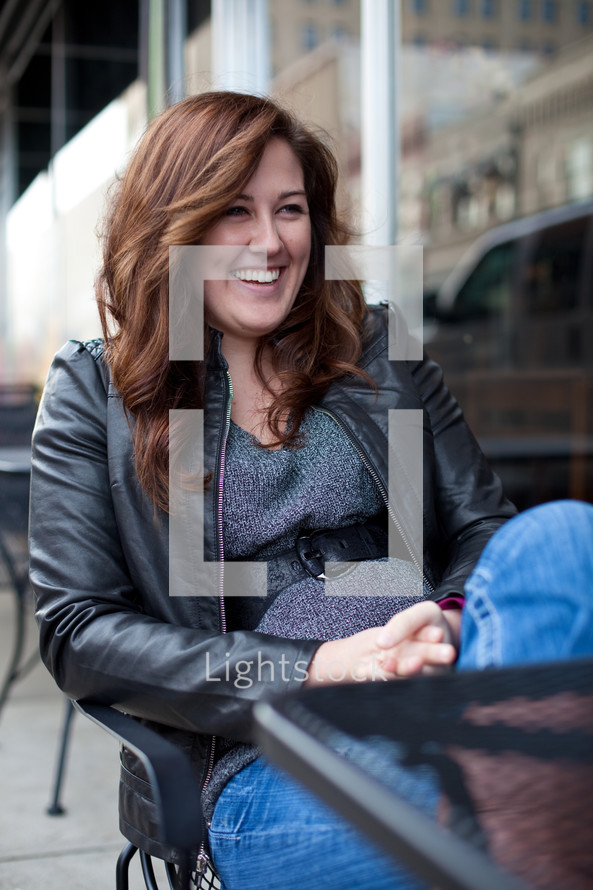 smiling woman sitting at an outdoor table 