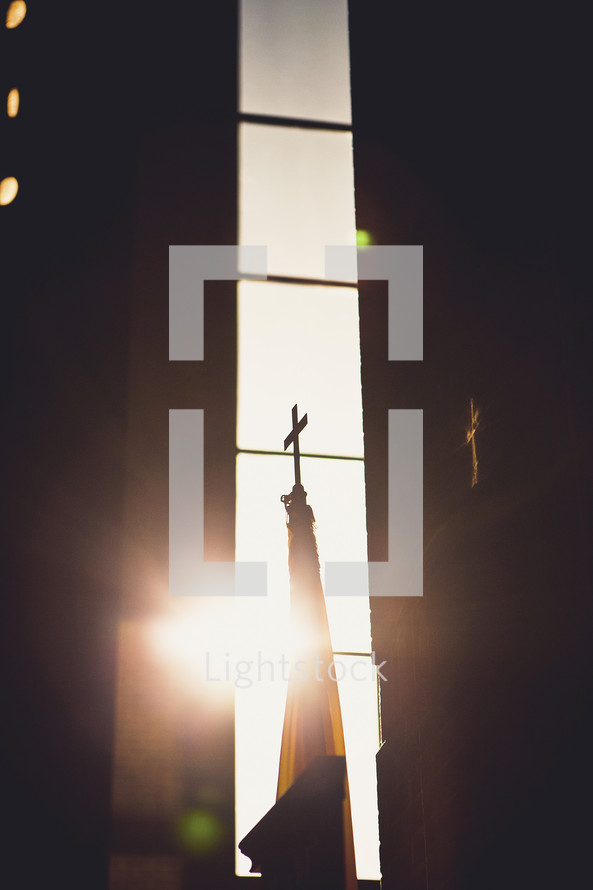 sun shining through a church window onto a cross