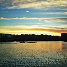 Rowing team on lake at sunset.
