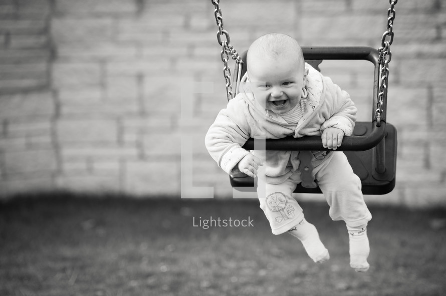 a happy baby swinging on a swing