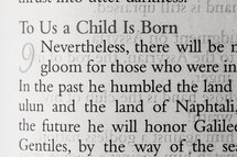 Magnified text of Bible open to Isaiah 9 to us a child is born