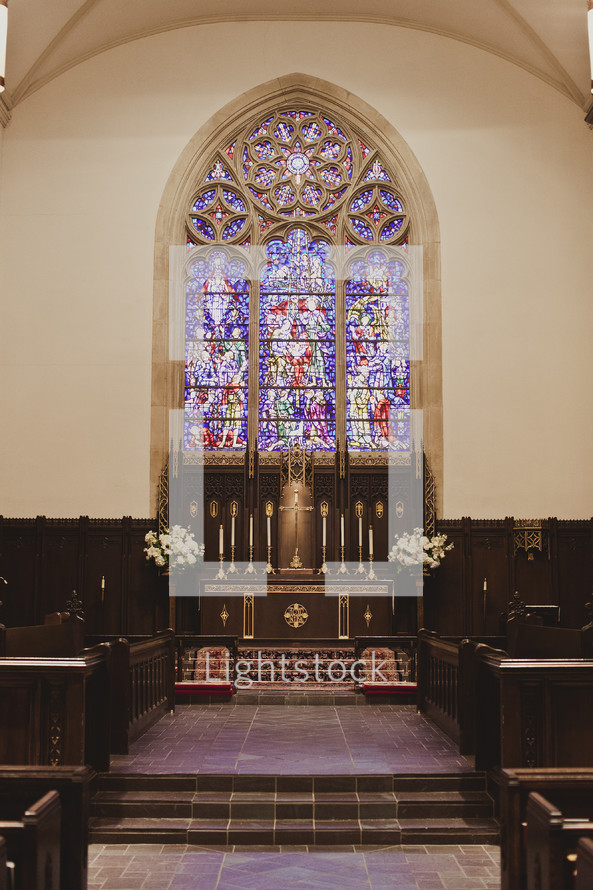 A church altar with a stained glass window in the background