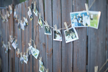 photos hanging on a line against a fence