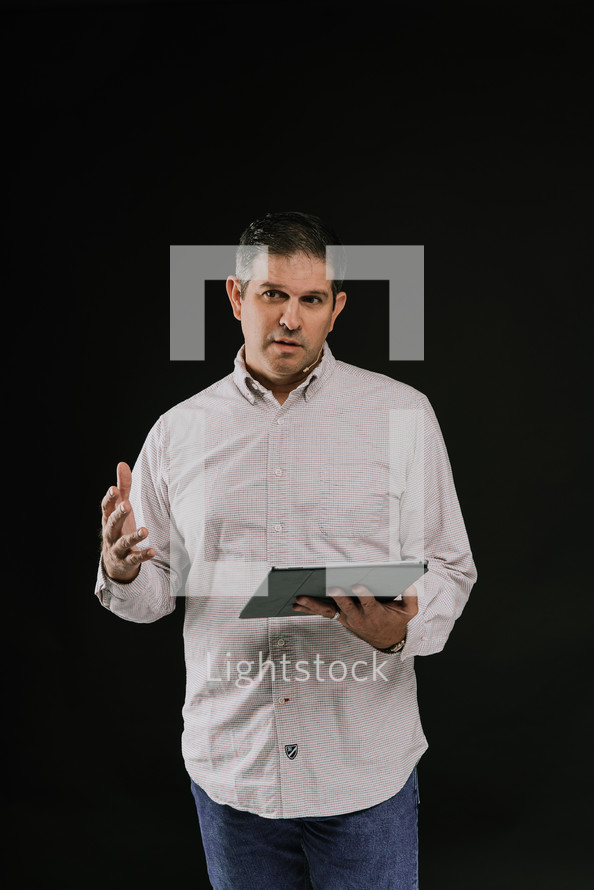 a man preaching holding a tablet 