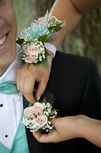 Woman hands pinning corsage on man's jacket