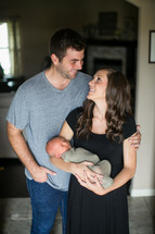 mother and father holding a swaddled newborn 