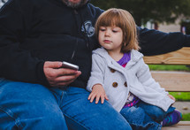 father and daughter looking at a cellphone screen 