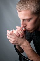 a man with head bowed and praying hands 