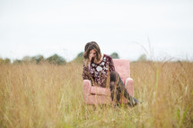 a young woman sitting in a chair in a field 