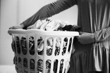 a woman holding a basket of dirty laundry 