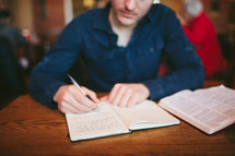 man writing in a journal 