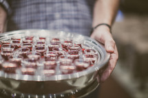 man holding a tray of communion cups 