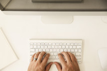 hands typing on a computer keyboard 