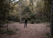 a girl standing alone in a forest 