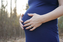 a woman with her hands on her pregnant belly 