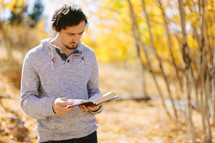 Man Reading Bible Outside During Autumn 