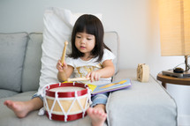 Little girl playing drum at home.Child development concept