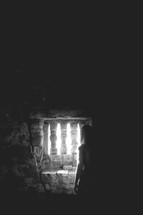 a woman standing in front of a window in an old cellar 