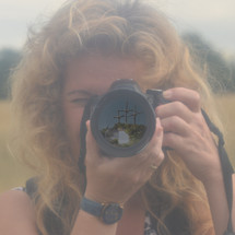 a woman taking a picture with a camera and three crosses in focus in the lens 