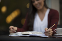 close up of a young woman reading a Bible and writing in a journal.