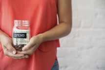 woman holding a spend money jar 