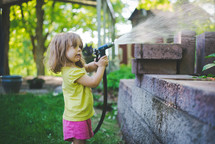 a little girl spraying a water hose 