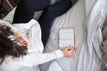 young woman reading a Bible in her bed 