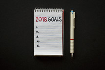 pen and 2018 goals on a notepad 