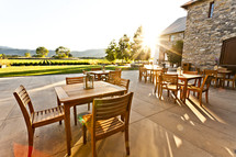 A patio with wood  tables and chairs at sunset over looking a vineyard napa valley