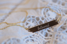 A necklace reading, "beloved," on a gold chain.