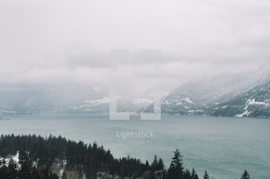foggy sky over a river and view of mountains in winter 