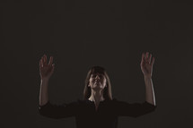 A woman standing with hands raised in worship to God