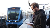 man reading a Bible waiting at a train station 