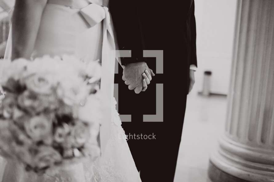 A bride and groom stand with hands held