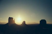 Silhouettes of buttes at sunset.