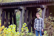young man standing near a railroad bridge 