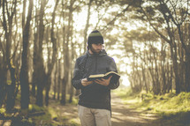 a man reading a Bible in a forest 